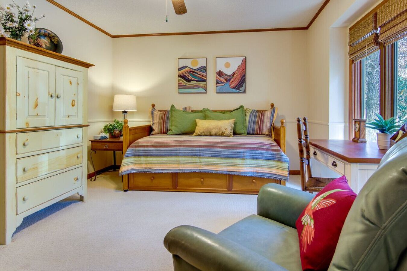 Une chambre à coucher avec un lit, une commode, une chaise et deux tableaux accrochés au mur.