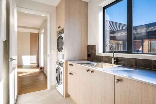 A modern kitchen with a built-in washer and dryer, a large window, and a view of the outside.