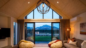 A spacious living room with a large window offering a mountain view, a cozy sofa, and two bean bags.