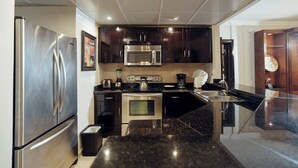 A modern kitchen with stainless steel appliances, dark wooden cabinets, and a granite countertop.