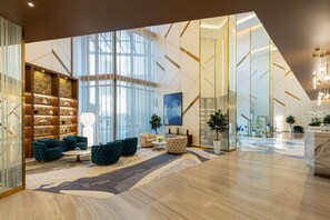 A spacious lobby with modern furniture, a large window, and a geometric wall design. - Damac Maison Aykon City Dubai (Dubai)