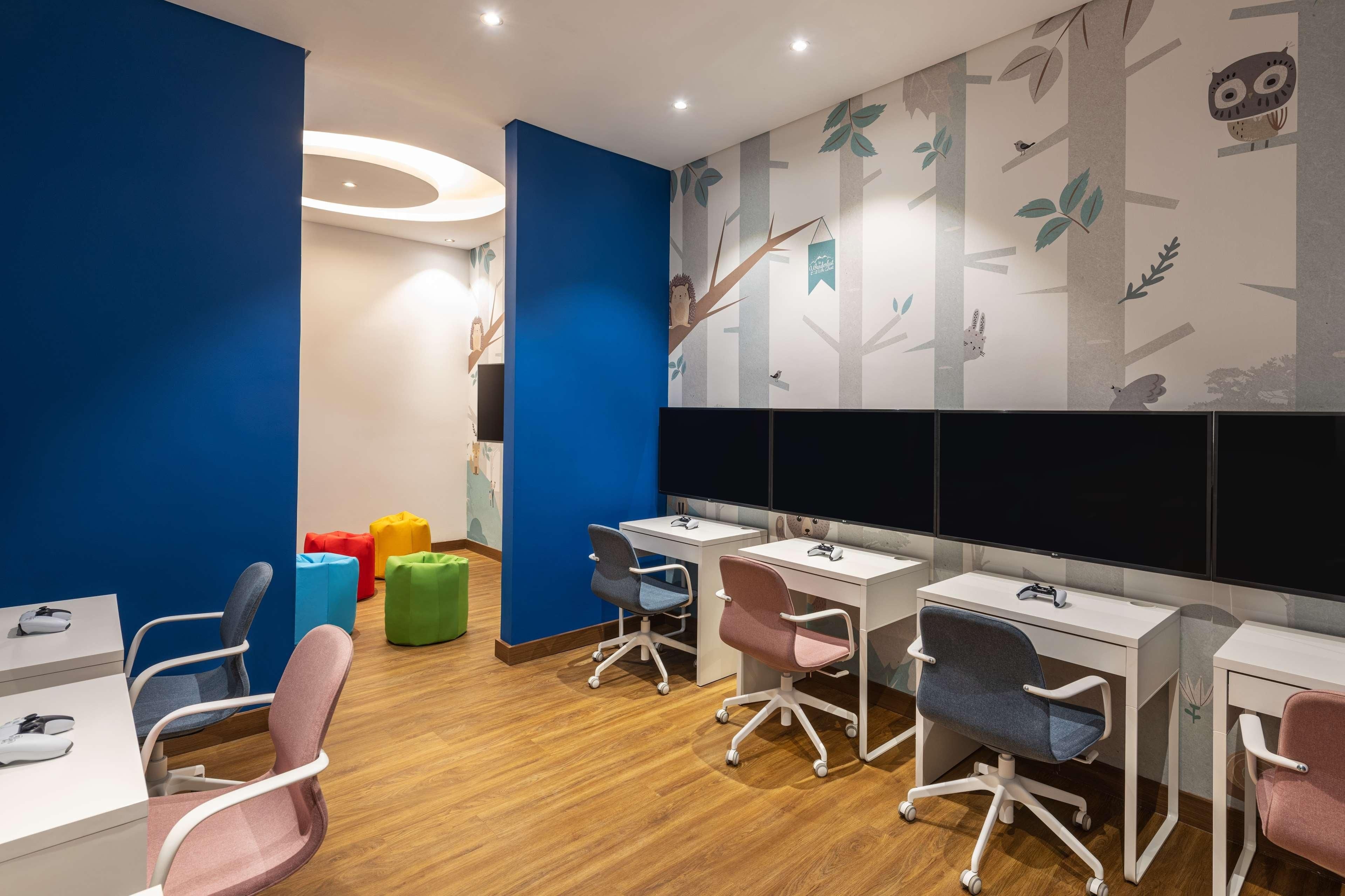 A children's play area with colorful seating, a large mural, and multiple workstations.