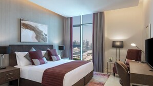 A modern hotel room with a large bed, a desk, a chair, and a TV. - Damac Maison Aykon City Dubai (Dubai)