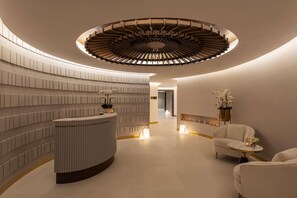 A modern reception area with a circular staircase, a reception desk, and seating area with decorative plants. - Damac Maison Aykon City Dubai (Dubai)