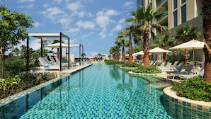 A swimming pool with tiled patterns, surrounded by palm trees and lounge chairs. - Damac Maison Aykon City Dubai (Dubai)