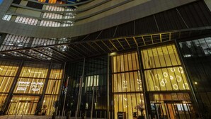 Un edificio moderno con varios pisos y ventanas amplias, que cuenta con una entrada destacada con puertas de vidrio y una fachada bien iluminada.