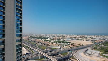 A high-rise building with multiple floors and large windows, overlooking a cityscape with a highway and a large open area.