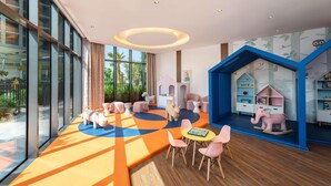 A children's playroom with a large window, a colorful carpet, and a small table with chairs. - Damac Maison Aykon City Dubai (Dubai)