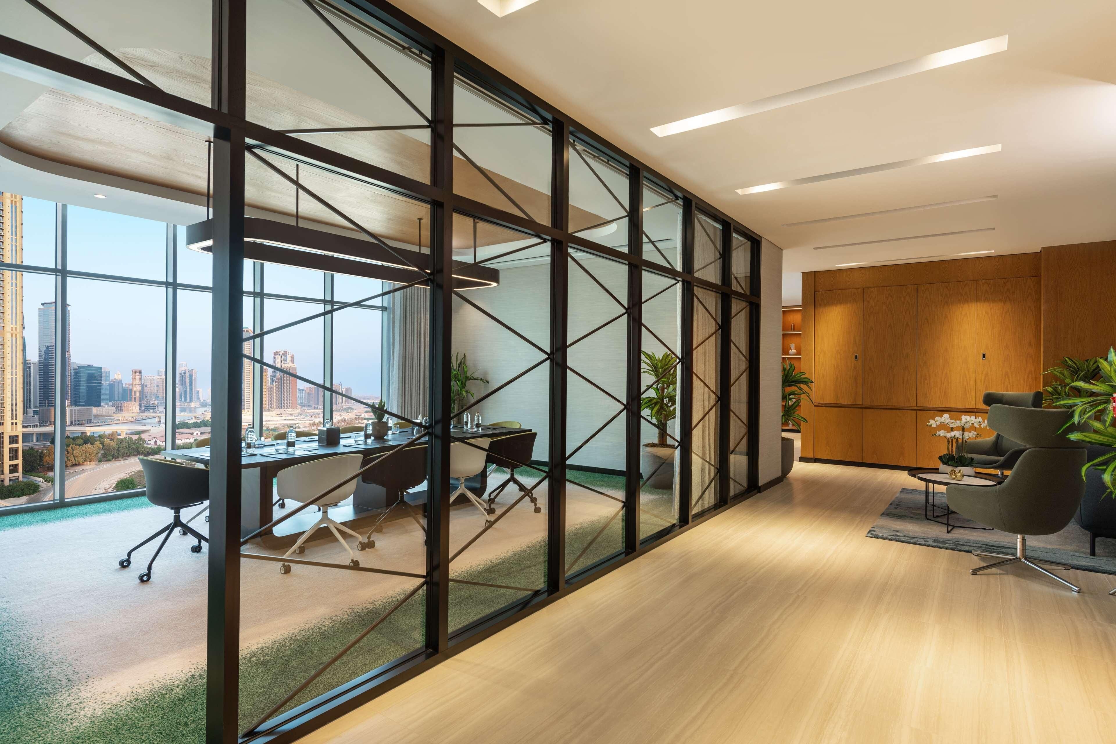 Een moderne kantoorruimte met een grote glazen wand, een vergadertafel, kantoorstoelen en uitzicht op de skyline.