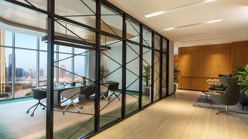 Een moderne kantoorruimte met een grote glazen wand, een vergadertafel, kantoorstoelen en uitzicht op de skyline.