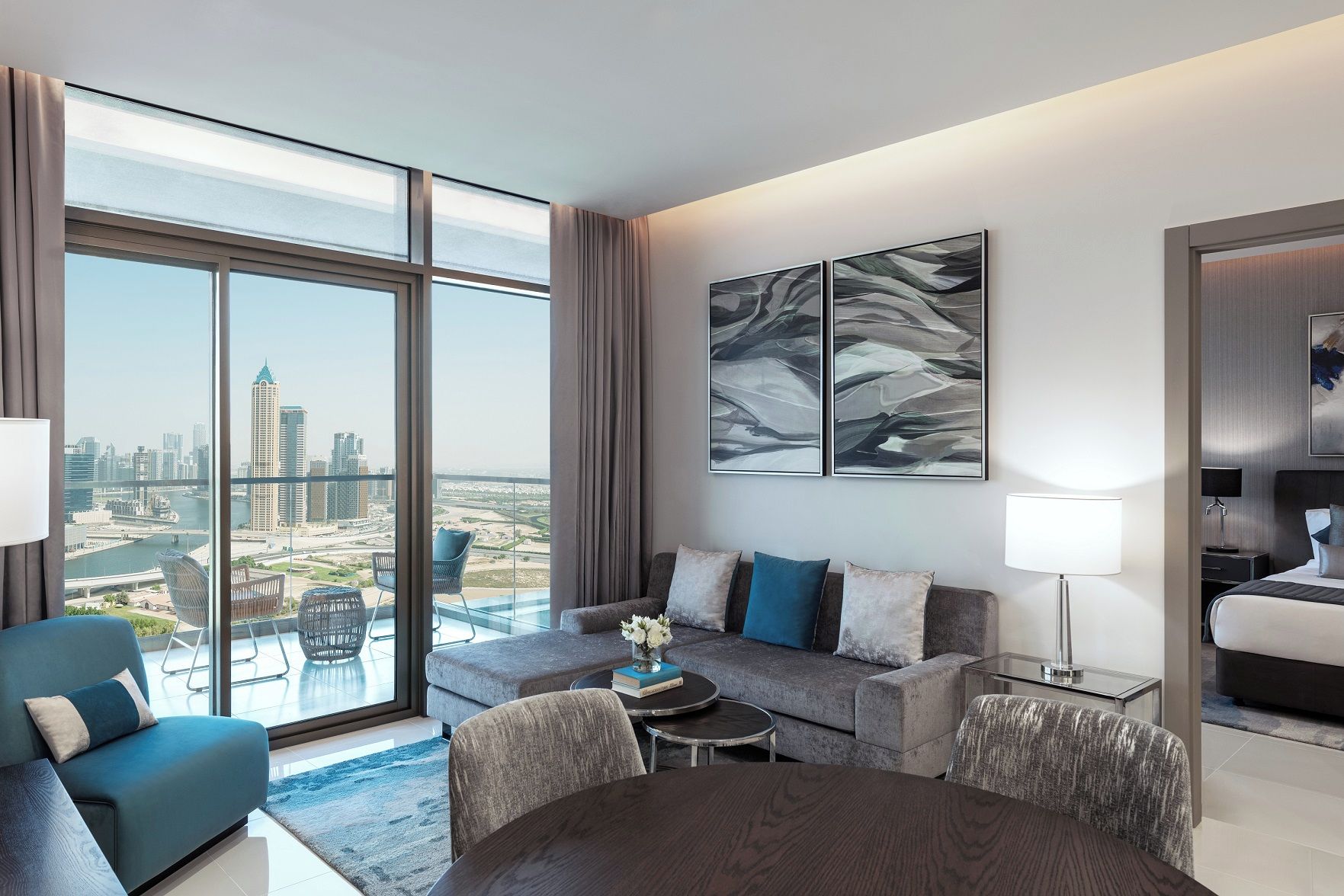 Een moderne hotelkamer met een ruim balkon, een zithoek, een eettafel en een bed.