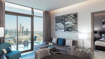 Een moderne hotelkamer met een ruim balkon, een zithoek, een eettafel en een bed.