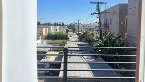 Blick vom Balkon auf ein Wohngebiet mit Gebäuden, einem parkenden Lastwagen und Stromleitungen.