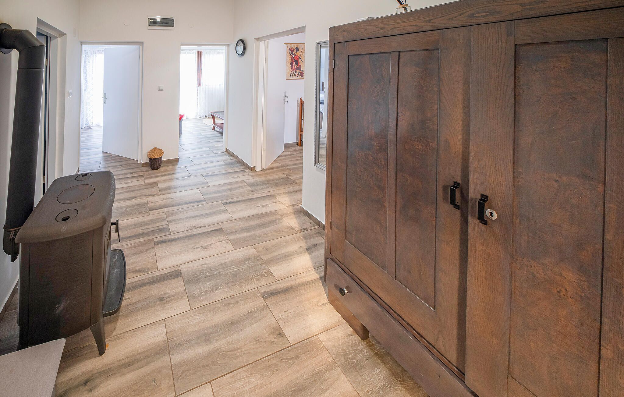 Un couloir doté d’un plancher en bois, d’une grande armoire en bois et d’une petite table sur laquelle se trouve un panier.