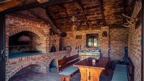 A rustic interior with a brick oven, wooden benches, a central table, and a hanging light fixture. - Stunning home in Slatinski Drenovac (Slatinski Drenovac)