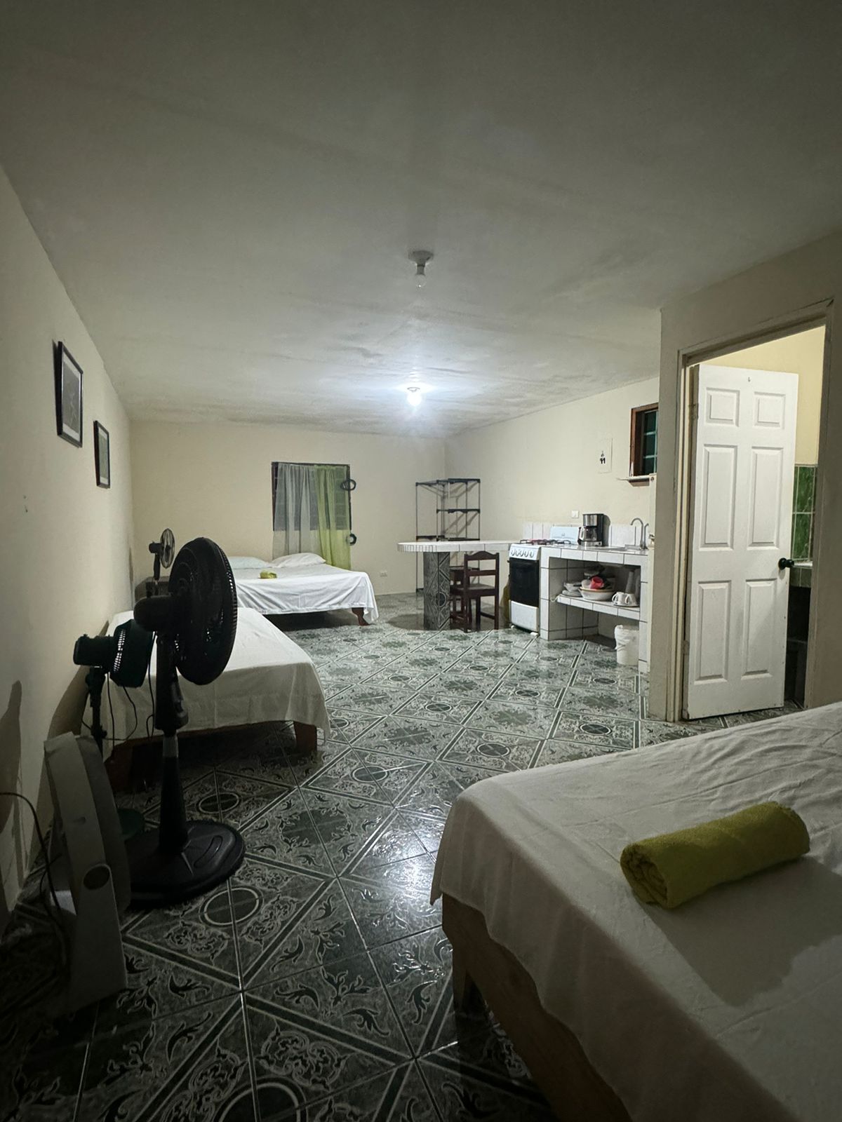 A compact hotel room with two beds, a desk, and a kitchenette.