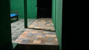 A narrow hallway with green walls and a tiled floor leading to a door with a metal gate. - Cozy "LORITO" Apartment at MANUEL ANTONIO / 4 People (Quepos)