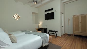 Quarto com duas camas, uma escrivaninha, uma cadeira, uma televisão e um guarda-roupa.