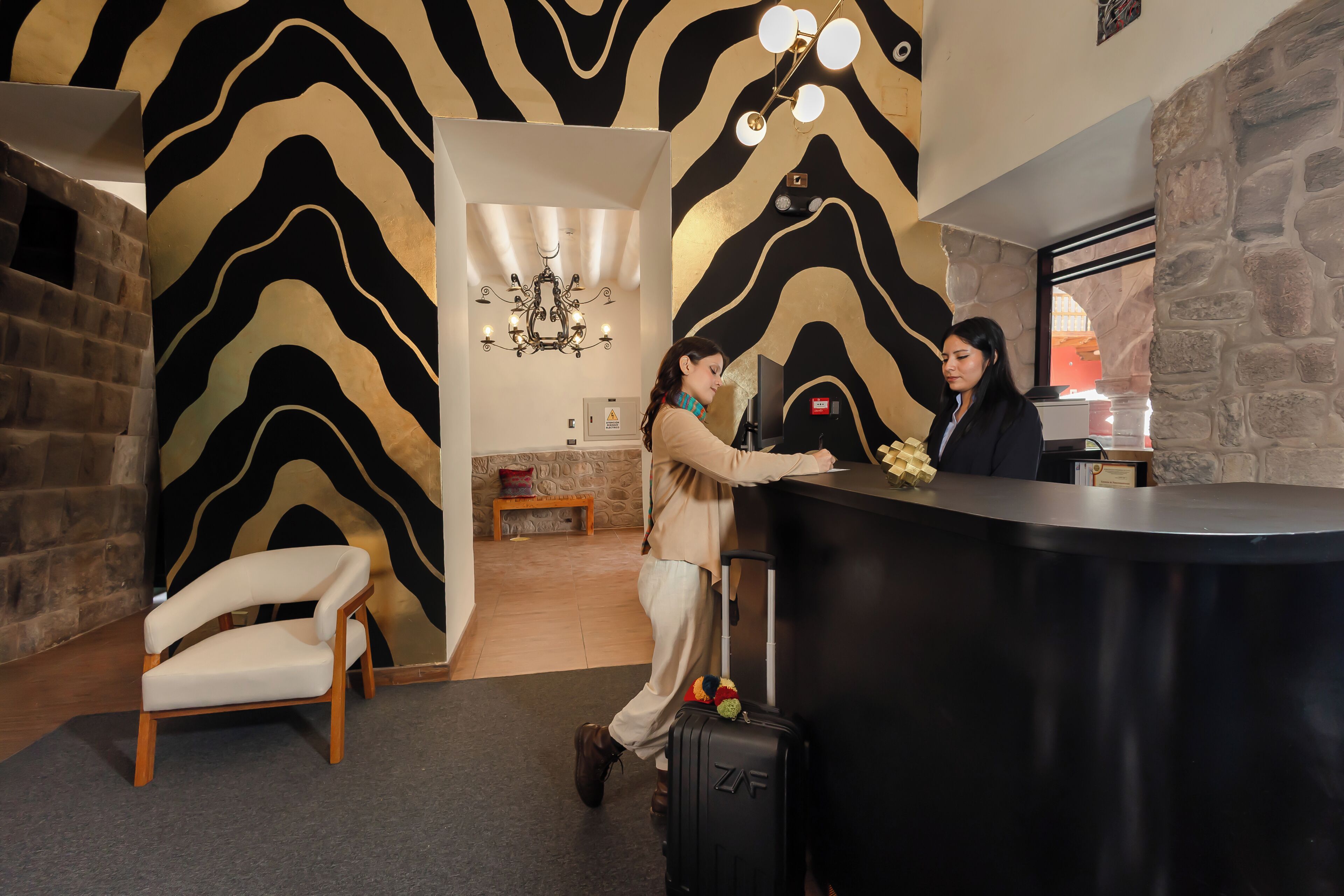 A reception area with a zebra-patterned wall, a chandelier, a bench, and a desk.