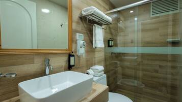 A modern bathroom with a large rectangular sink, a toilet, and a glass-enclosed shower area.