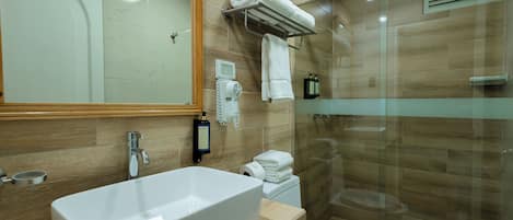 A modern bathroom with a large rectangular sink, a toilet, and a glass-enclosed shower area.