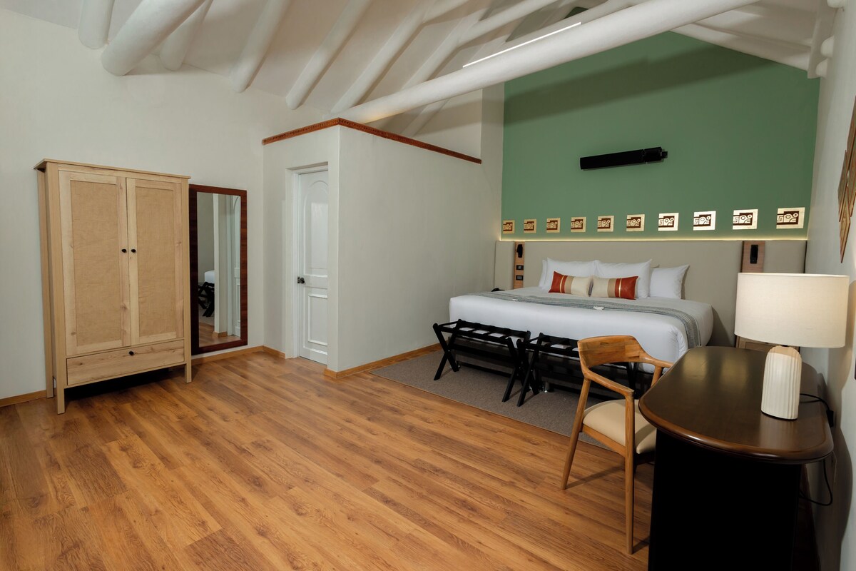 Un dormitorio con cama, armario de madera, escritorio con lámpara y pared decorativa verde.