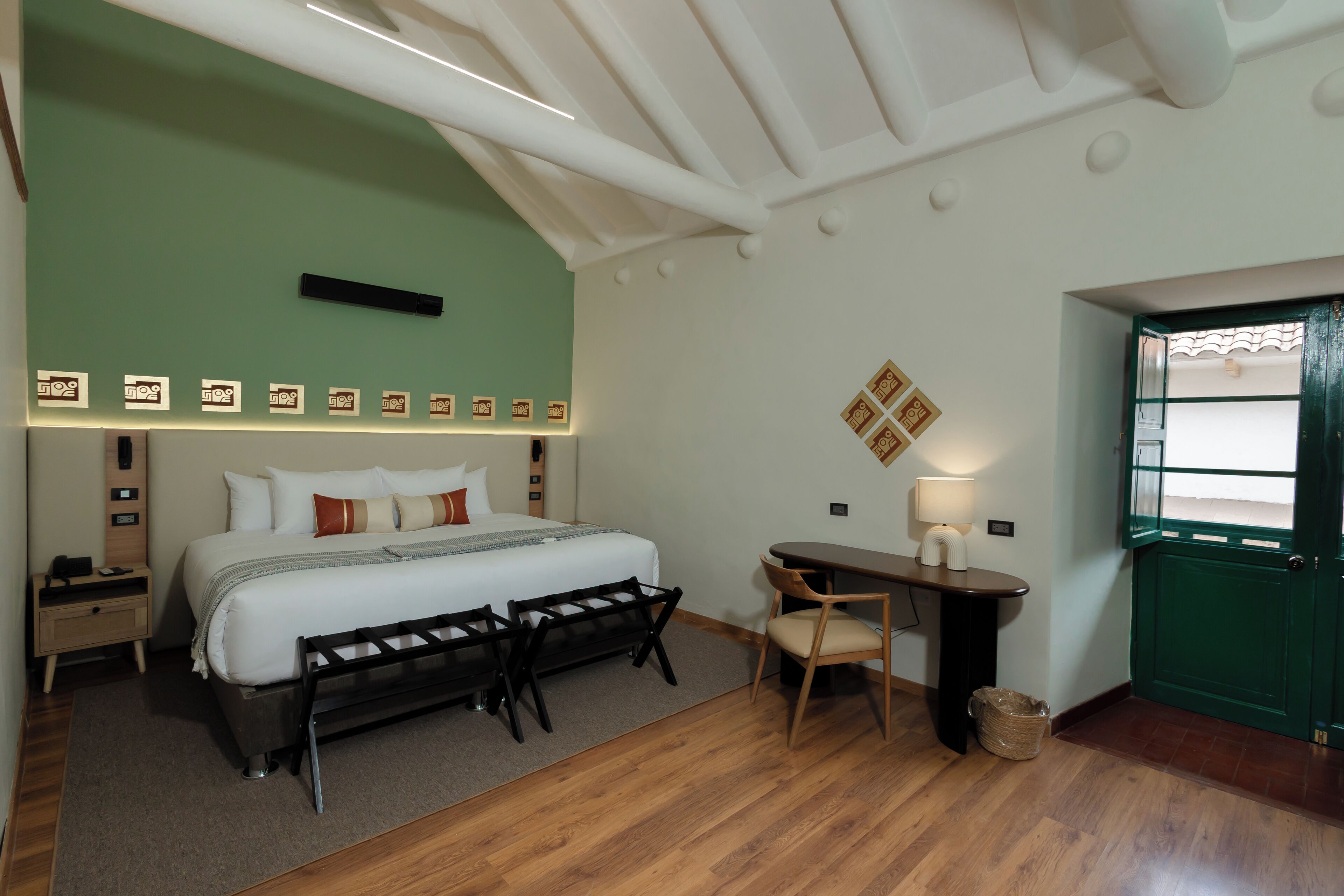 A hotel room with a bed, bedside tables, a desk, and a chair.