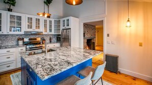 Een moderne keuken met granieten aanrecht, roestvrijstalen apparatuur en een blauw eiland.