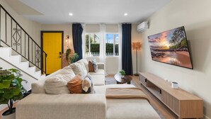 A living room with a sofa, a coffee table, and a TV mounted on the wall.