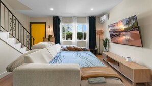 A modern bedroom with a bed, sofa, and a large window with curtains.