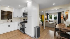 A modern kitchen with white cabinets, a built-in oven, and a compact refrigerator.