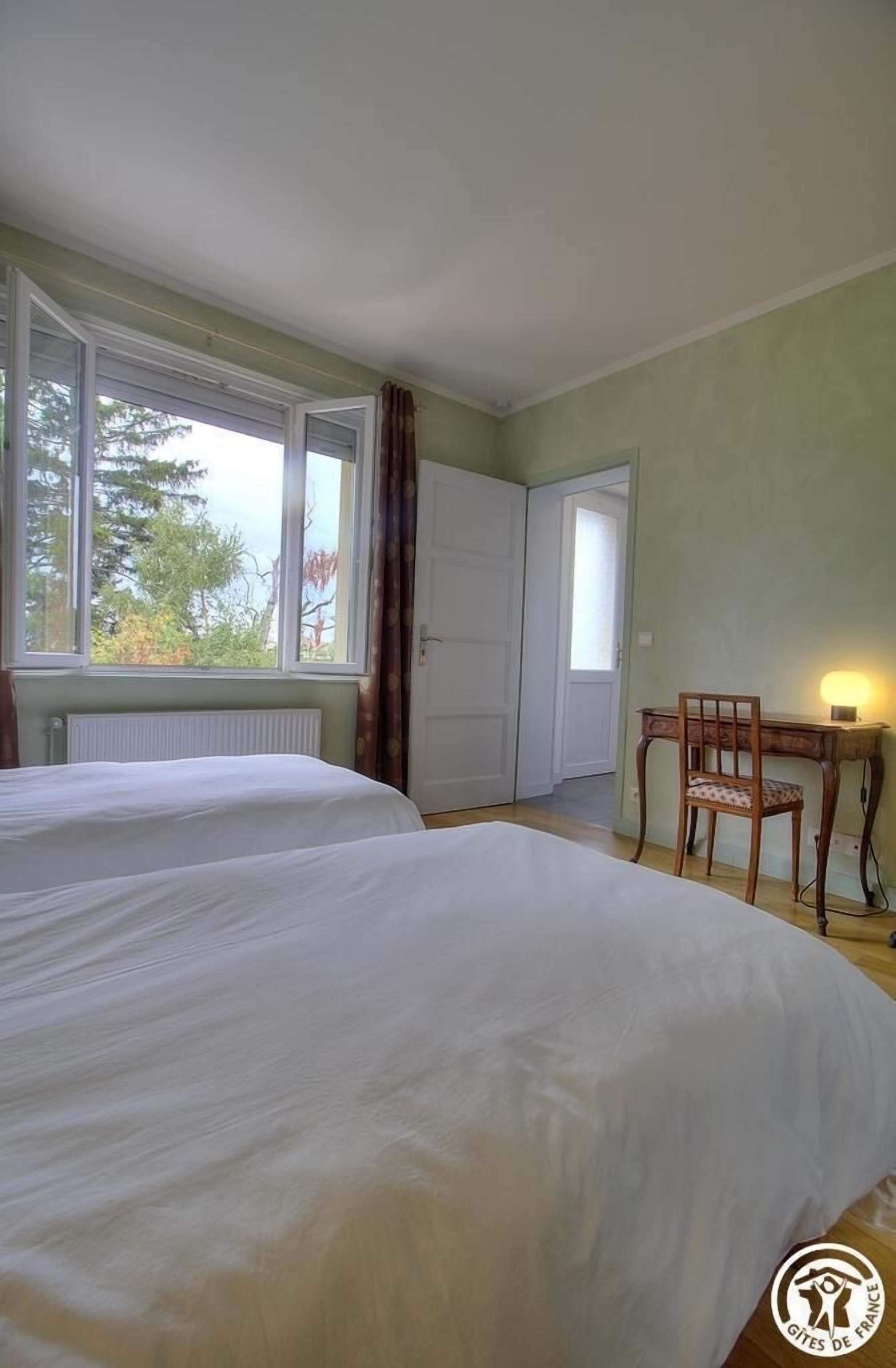 A room with two beds, a desk, and a chair.