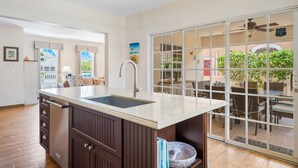 A kitchen with a large island, a dining area with wicker furniture, and a sliding glass door to a patio.