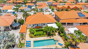 A residential area with houses featuring orange tiled roofs, a swimming pool, and solar panels.