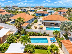 Um bairro residencial com piscina, palmeiras e vista para o mar.