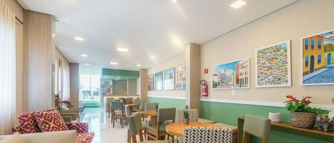 A hotel lobby with a dining area, seating arrangements, and artwork on the walls.