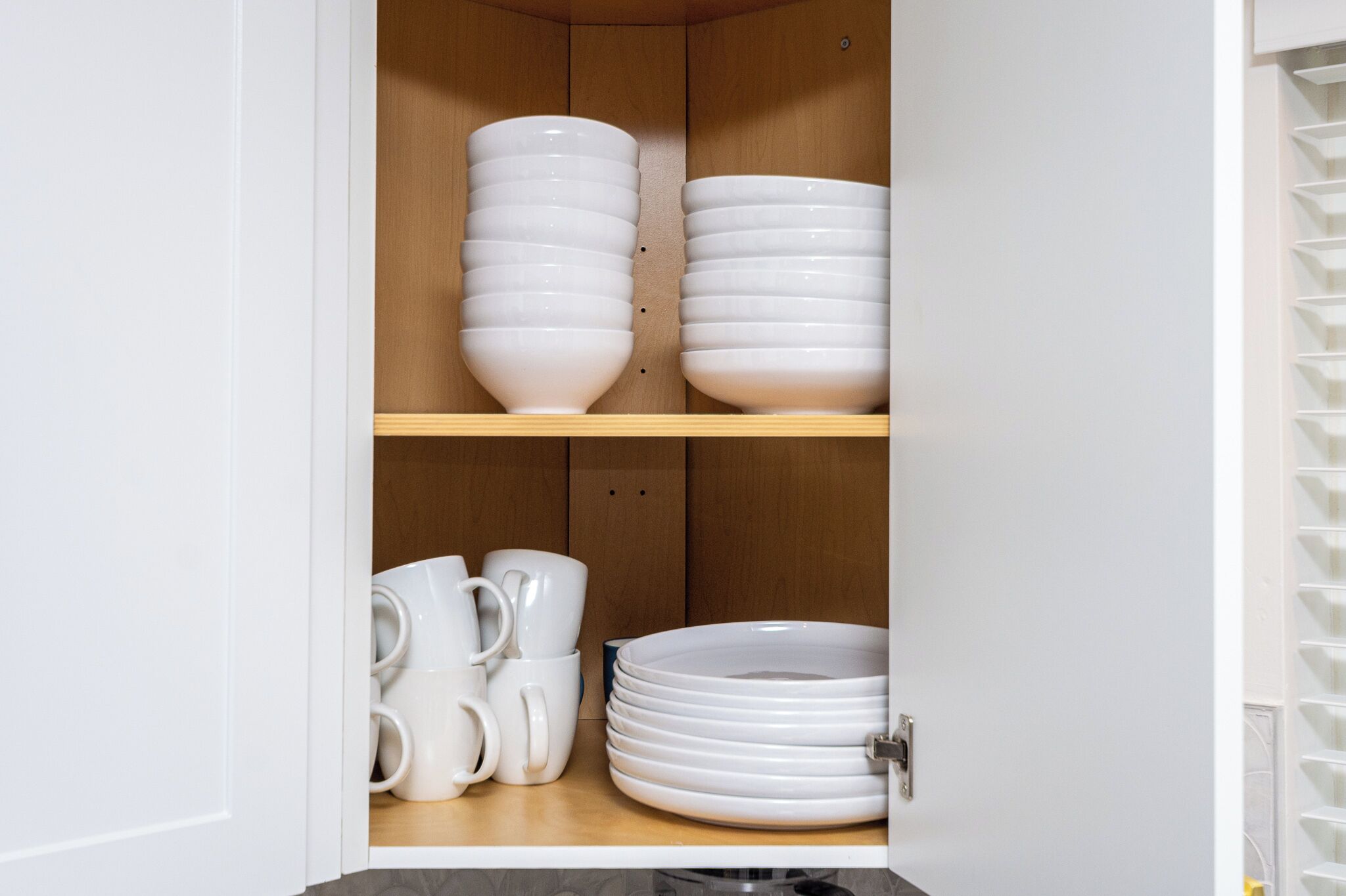 Ein Küchenschrank mit weißen Schüsseln und Tellern.