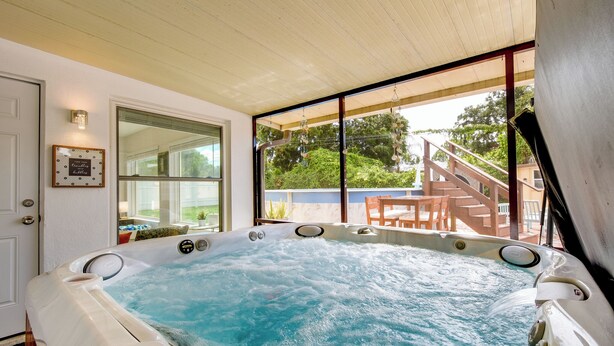 A hot tub with a view of a wooden deck and outdoor furniture.