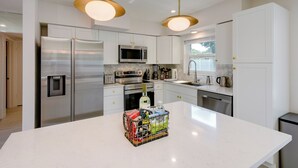 A modern kitchen with white cabinets, stainless steel appliances, and pendant lighting.