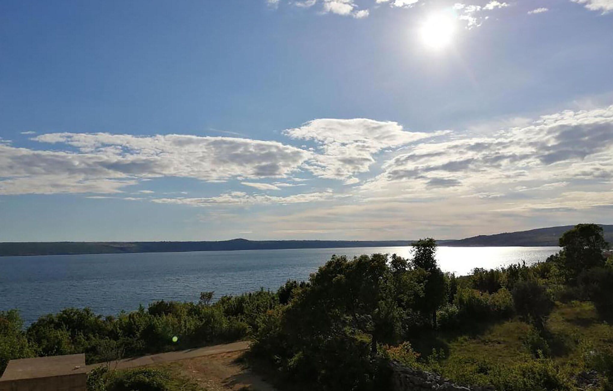 Vista de un lago con cielo despejado y nubes dispersas.