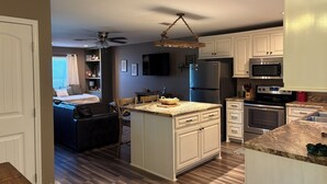 A modern kitchen with white cabinets, a granite countertop, and stainless steel appliances. - The Cottage at The Stables - Charming 1 bedroom - Sleeps 5 (Vancleave)