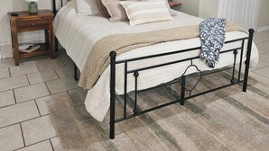 Un dormitorio con cama, mesitas de noche, un cabecero y un cuadro en la pared, además de una puerta.