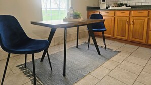 Una cocina con armarios de madera, una cafetera y dos sillas azules alrededor de una mesa.