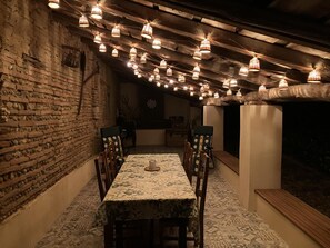 Un coin repas au style rustique, avec un mur en briques, des poutres en bois au plafond et une nappe à motifs.