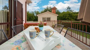 A balcony with a table set for two, featuring two coffee mugs and a decorative plant. - Cozy home in Sveti Bartol (Sveti Bartol)