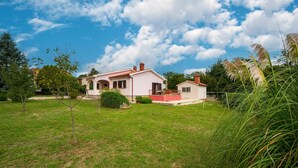 A two-story house with a red-tiled roof, a small attached garage, and a well-maintained lawn. - Cozy home in Sveti Bartol (Sveti Bartol)