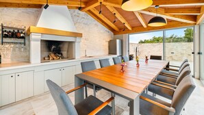 A modern kitchen with a large island, stone walls, and a wooden ceiling.