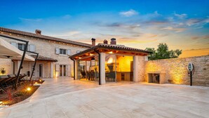 A stone house with a covered patio, outdoor seating, and a stone wall.