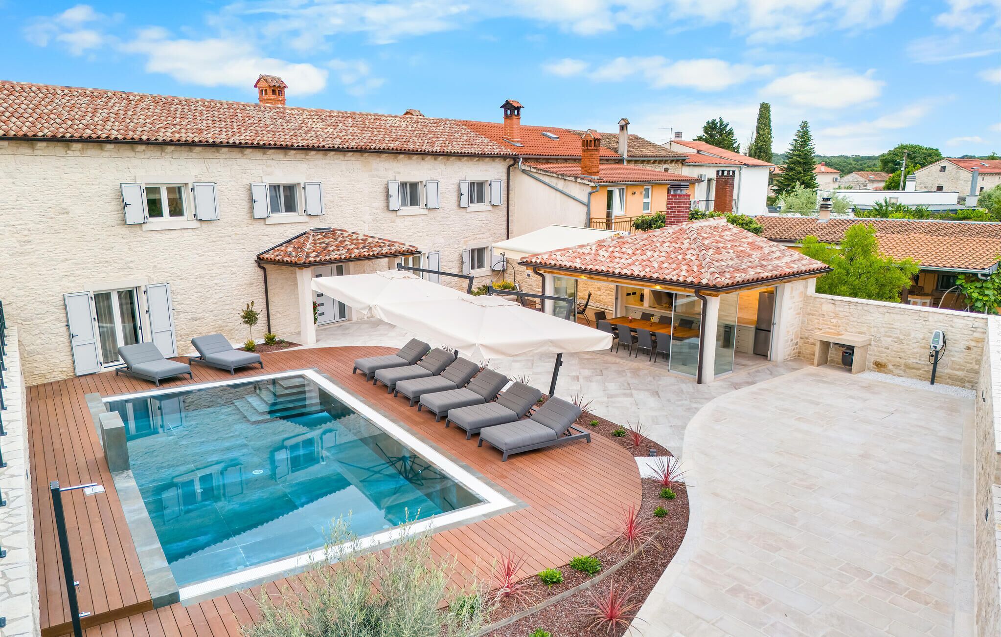 Ein Wohnhaus mit Swimmingpool, Sitzgelegenheiten im Freien und einer überdachten Terrasse.
