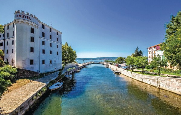 A building with a sign reading "KAŠTEL" next to a canal with boats.